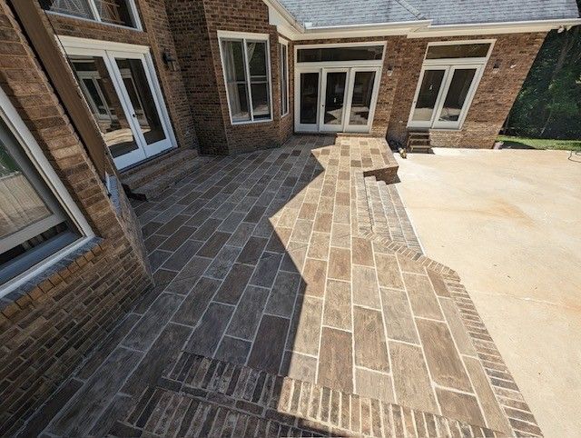 A brick house with a newly installed flagstone patio and stairs leading to a concrete driveway.