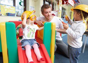 two kids playing on slides with teacher