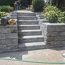 Stone steps with retaining walls and plants, leading up to a garden path.