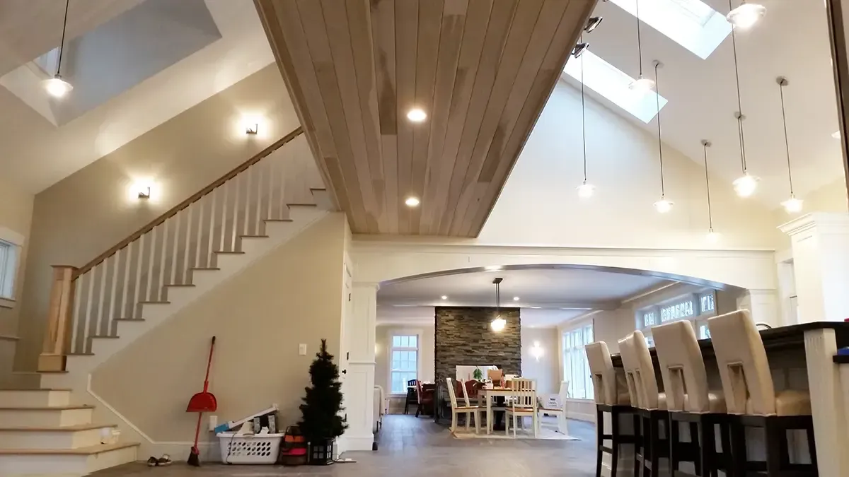 Spacious interior with stairs, wood ceiling, skylights, hanging lights, and a dining area visible.