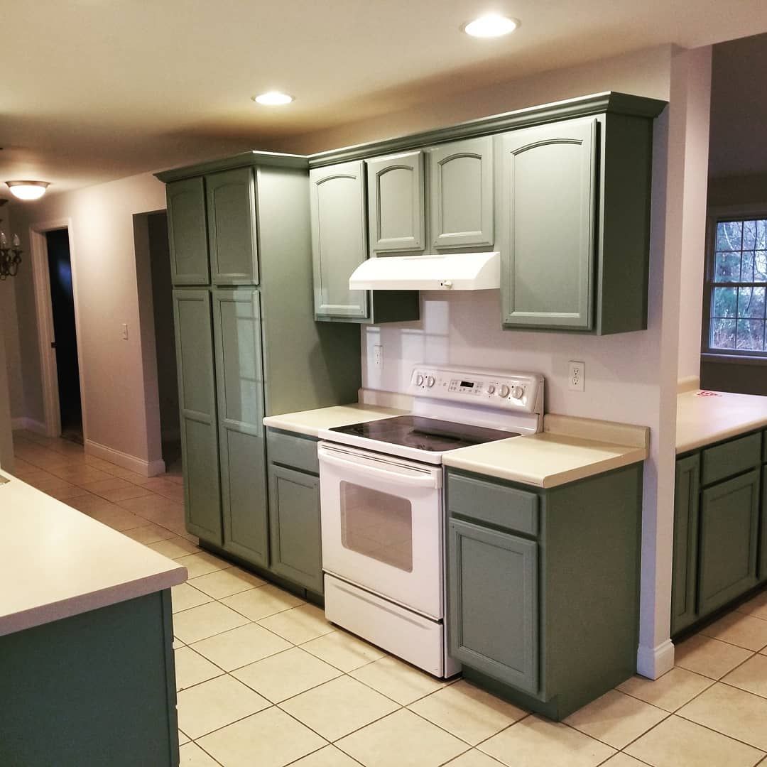 Kitchen with sage green cabinets, white appliances, and light countertops.