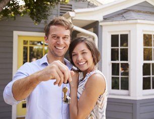 Couple with keys standing outside new home