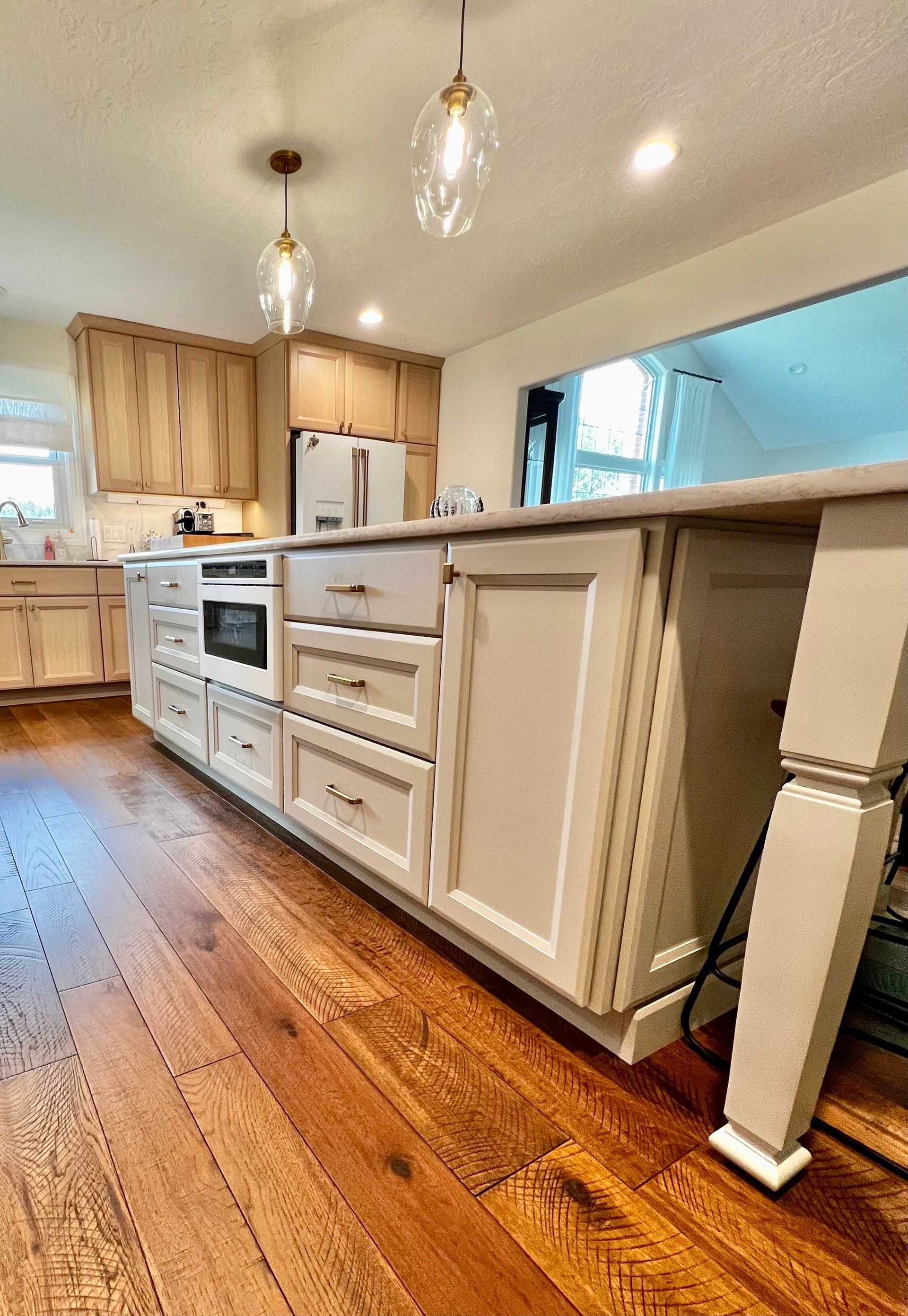A kitchen island with white cabinets, drawers, and a wooden countertop, set on warm-toned wood flooring.