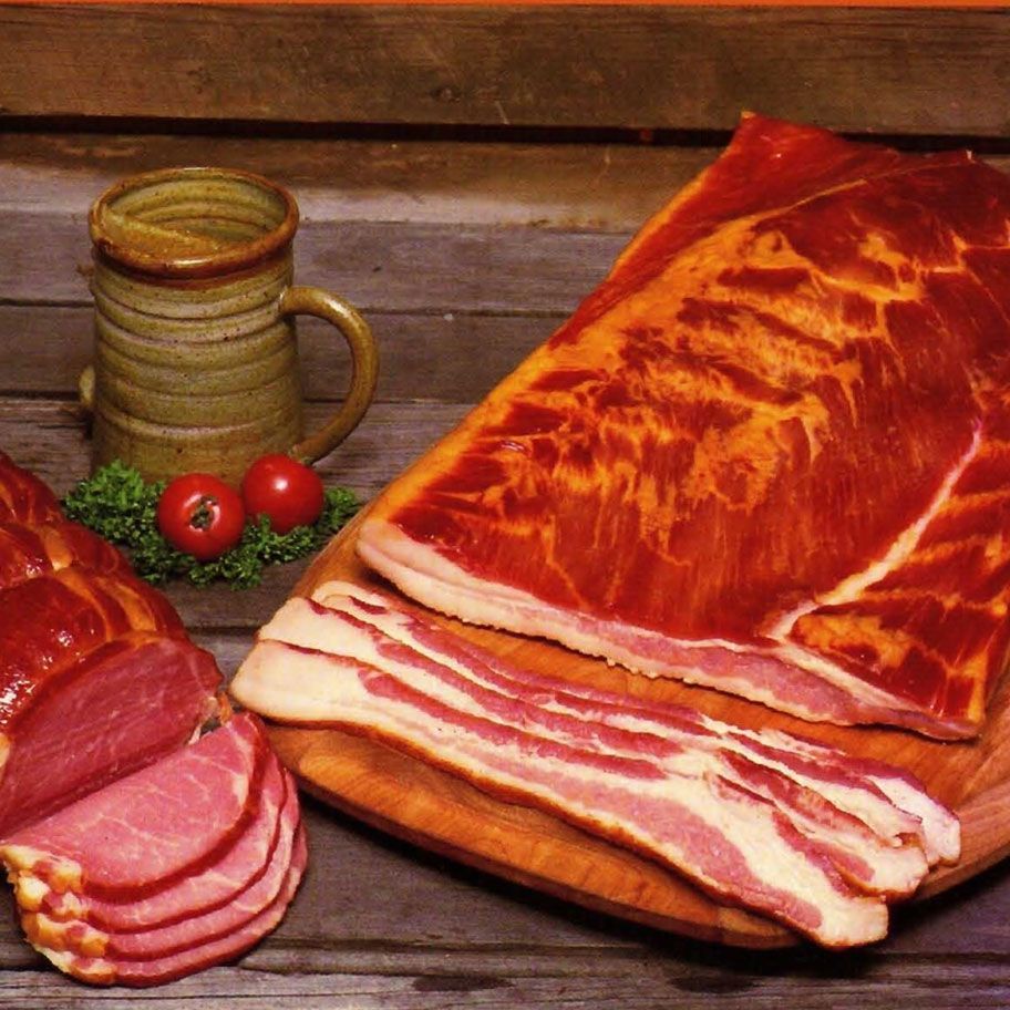 Sliced bacon on a cutting board next to a mug