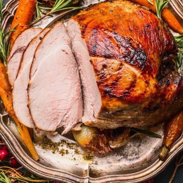A roasted turkey is sitting on a white plate on a table.