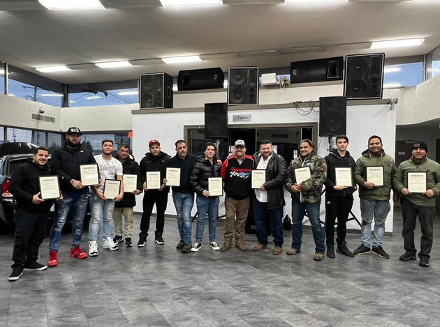 Group of people holding certificates in a hall, standing in a line for a group photo.