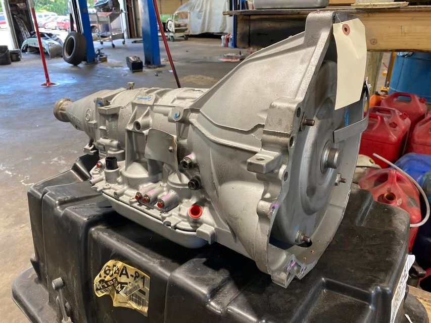 Silver car transmission on a black stand in a workshop garage