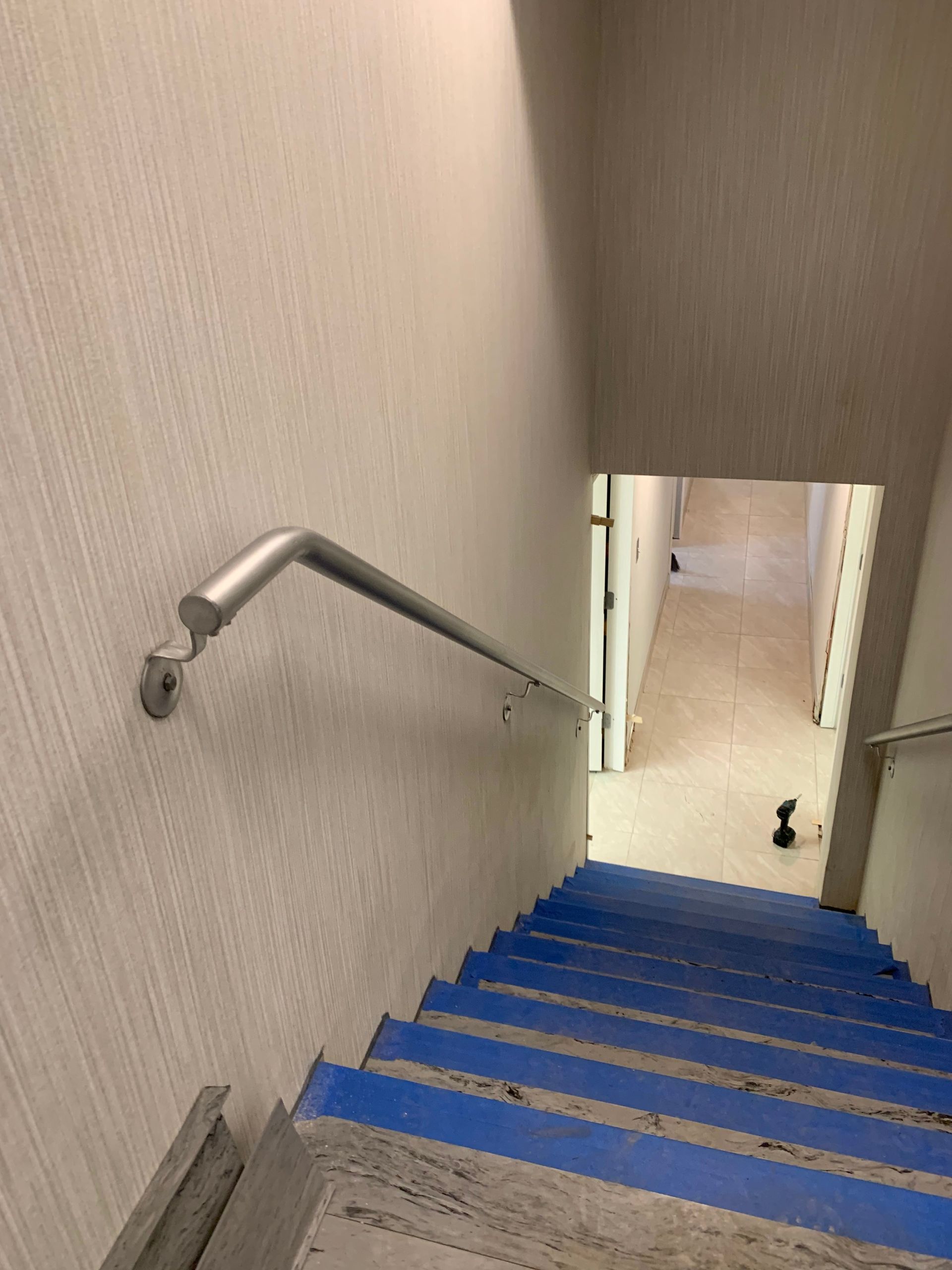 Steep blue-carpeted stairway with a silver ADA accessibility handrail installation in New Jersey
