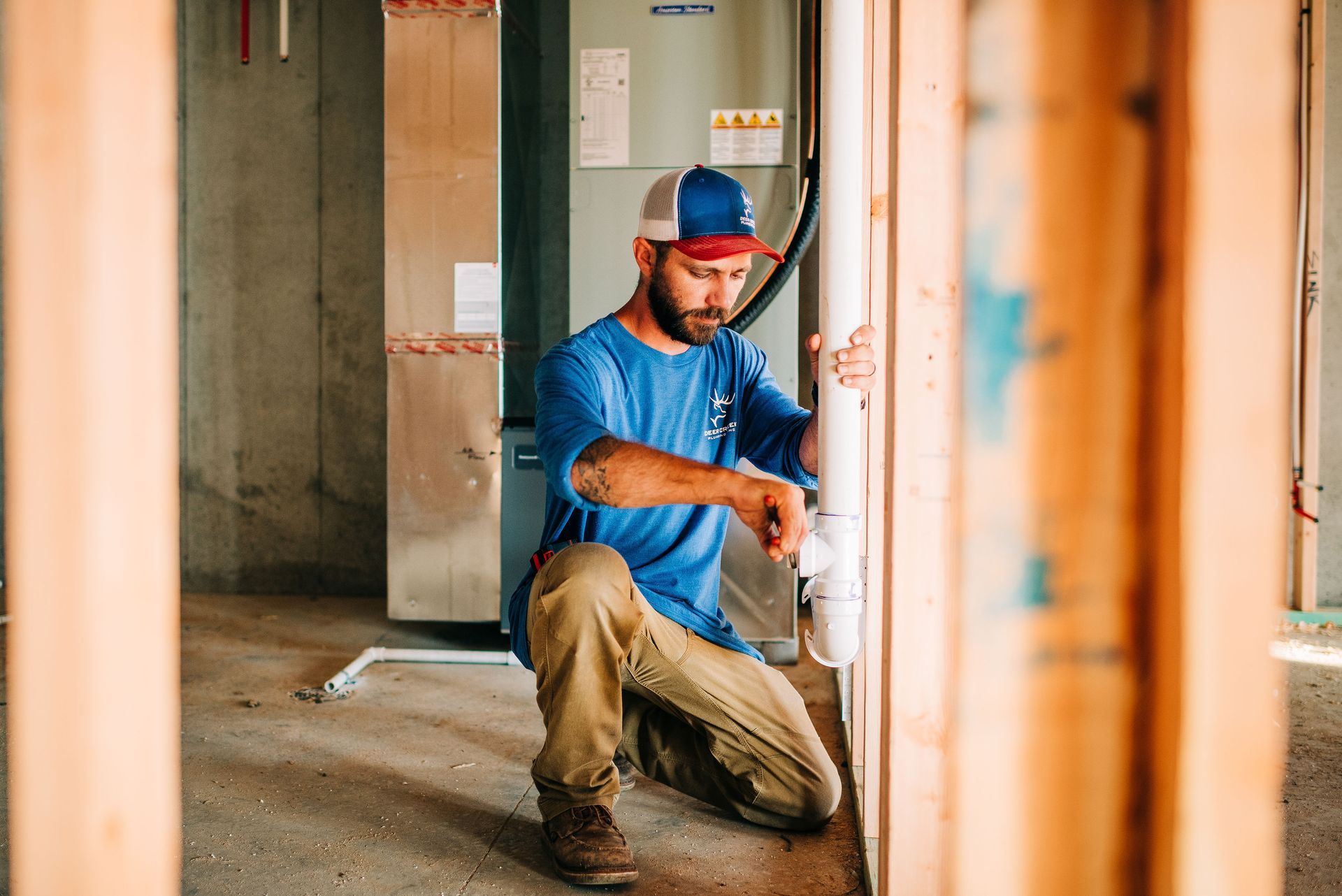 A man is kneeling down in a room while working on a pipe.