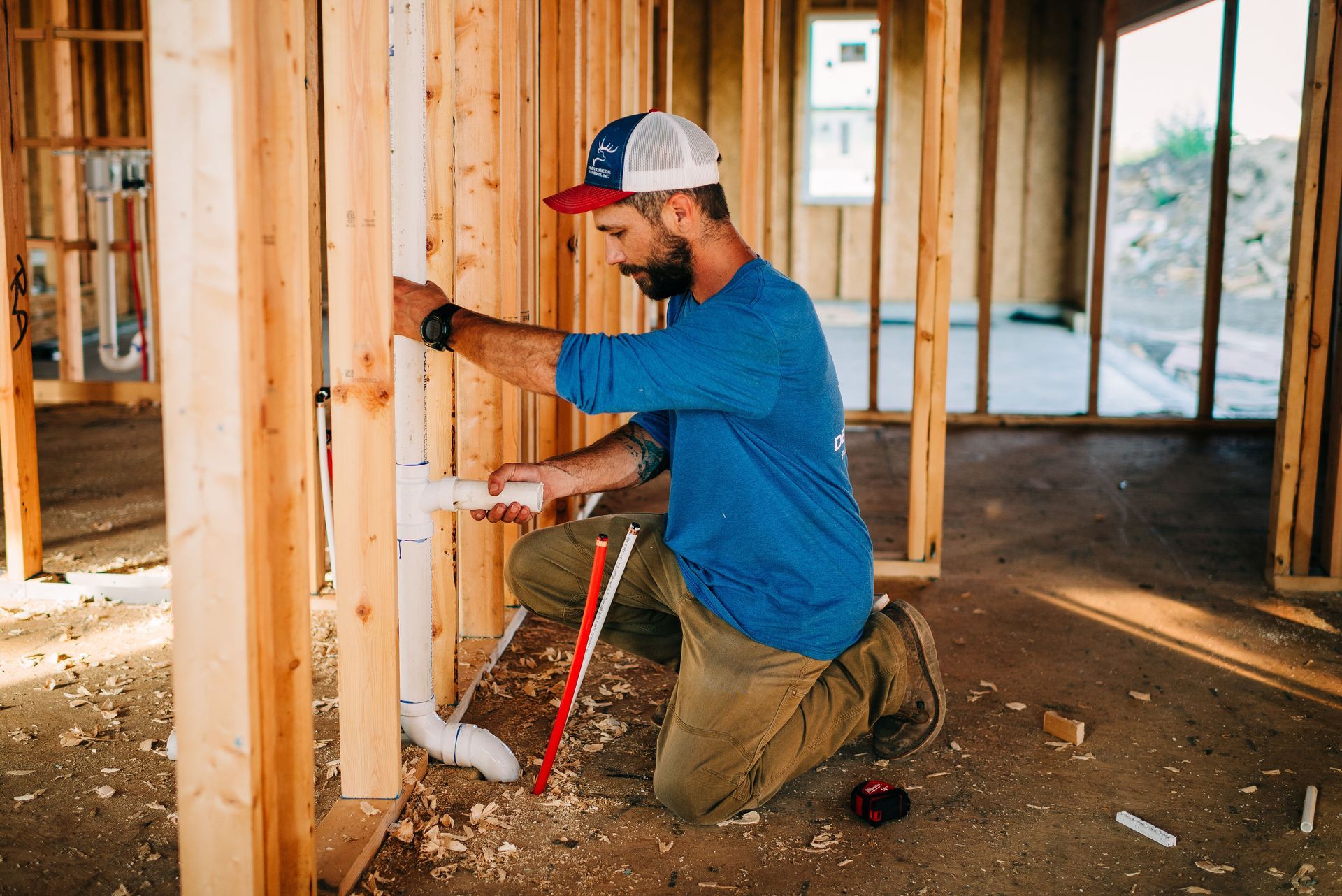 A man is working on a pipe in a house under construction.