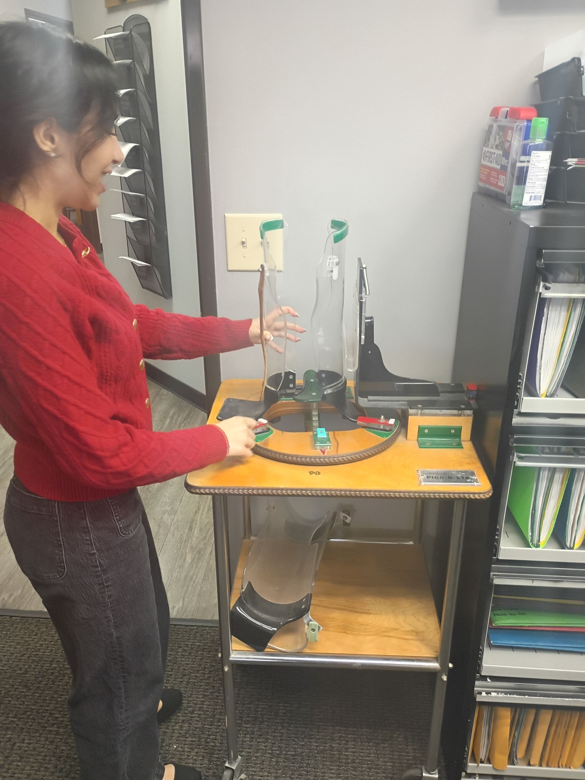Woman in red sweater operating a vision testing device in a clinic, smiling.