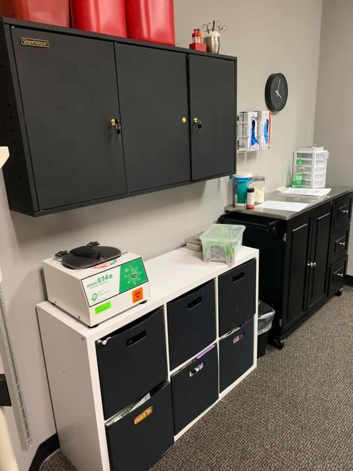 A medical lab corner featuring cabinets, a centrifuge, and drawers for supplies.