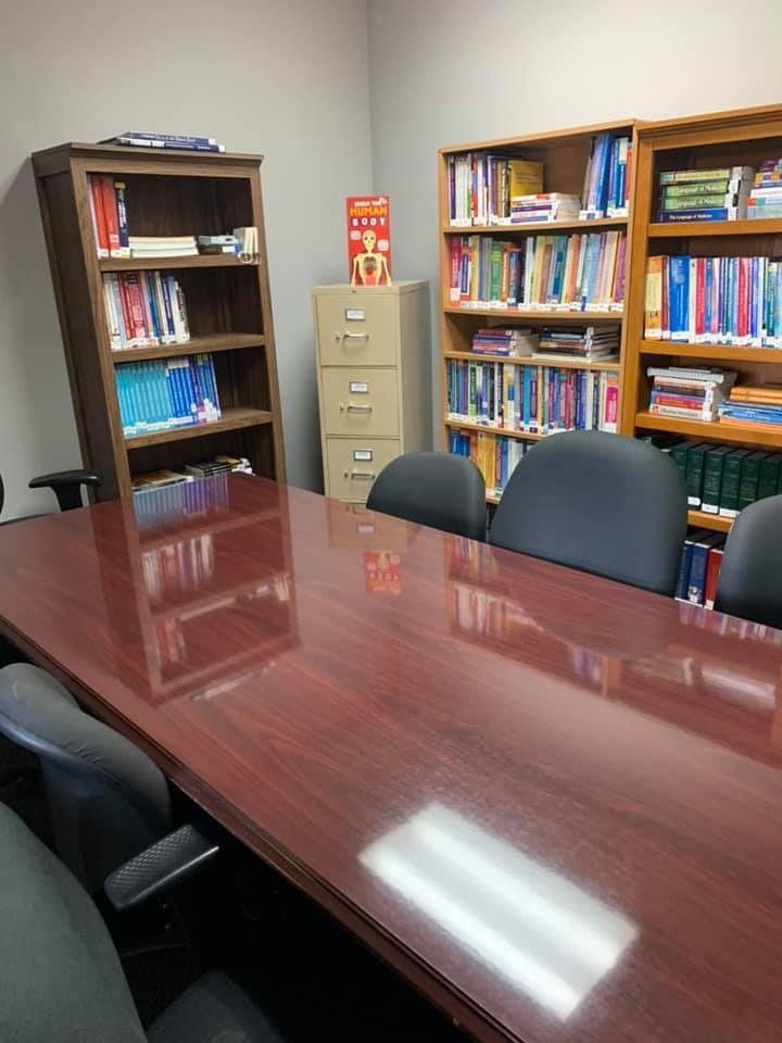 Conference room with large table and chairs; bookshelves and file cabinet in the background.