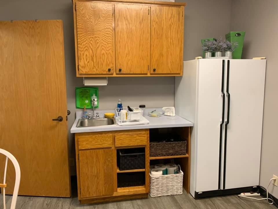 Small kitchenette with wooden cabinets, sink, and a refrigerator.
