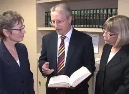 Group of people posing in front of a bookshelf. Several are in business attire.