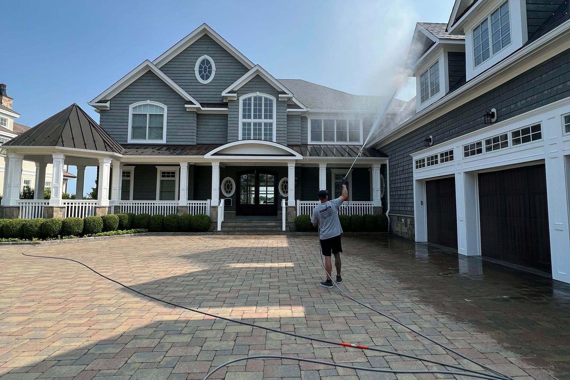 A person is cleaning a brick walkway with a high-pressure washer.