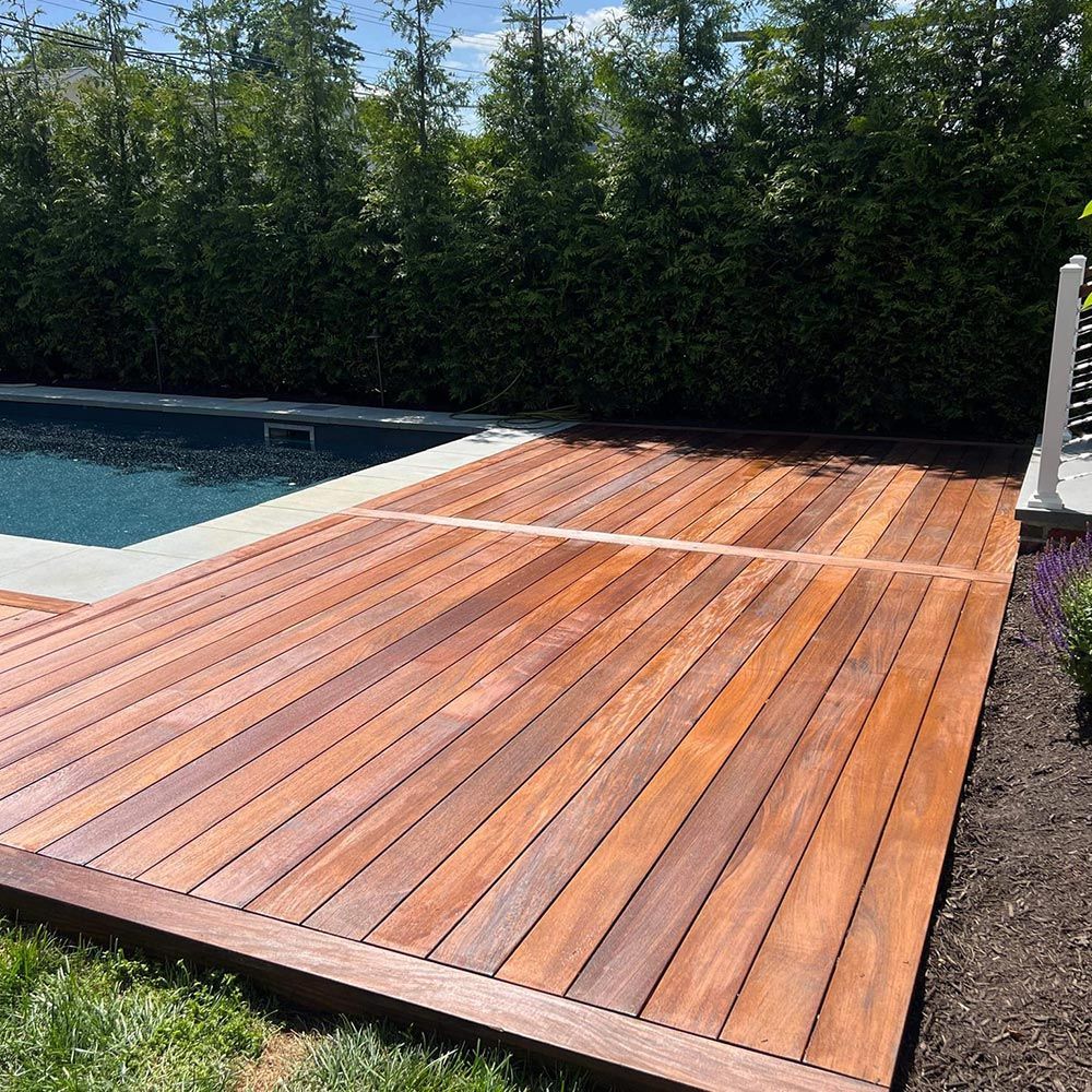 A wooden deck with a swimming pool in the background