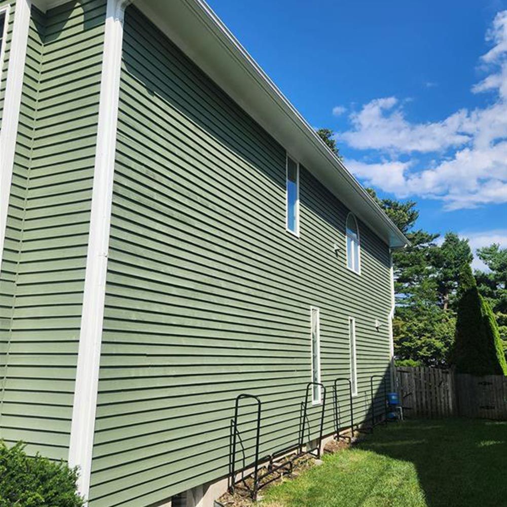 A green house with white trim is sitting on top of a lush green lawn.