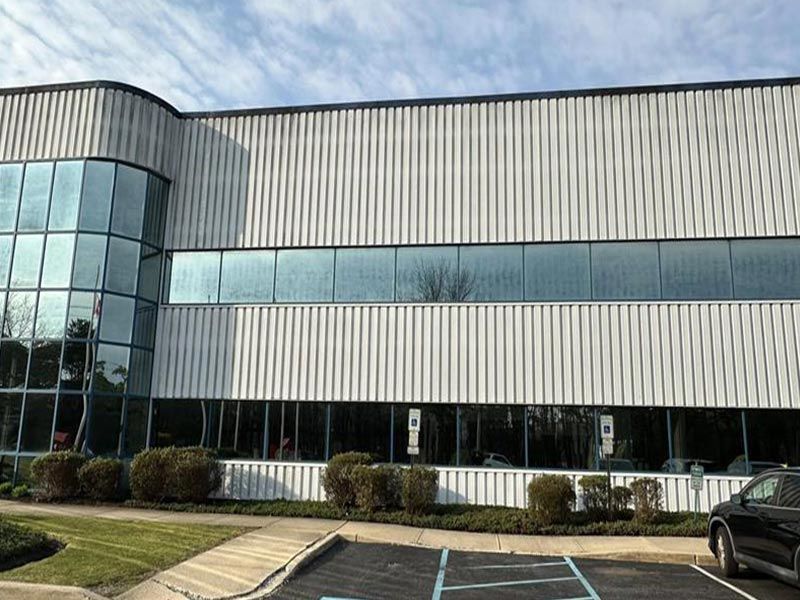 A large white building with a lot of windows and a car parked in front of it.