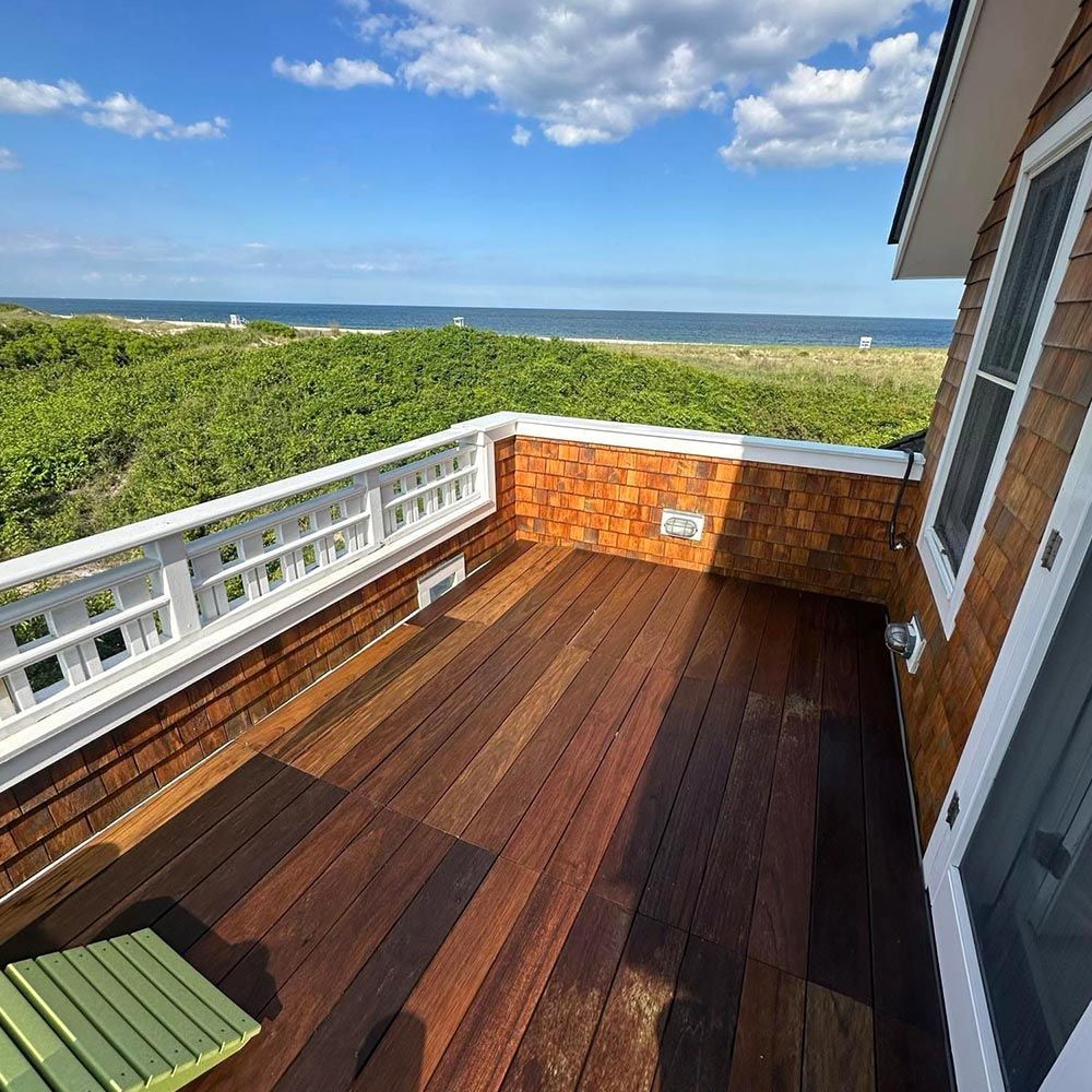 A balcony with a view of the ocean and trees