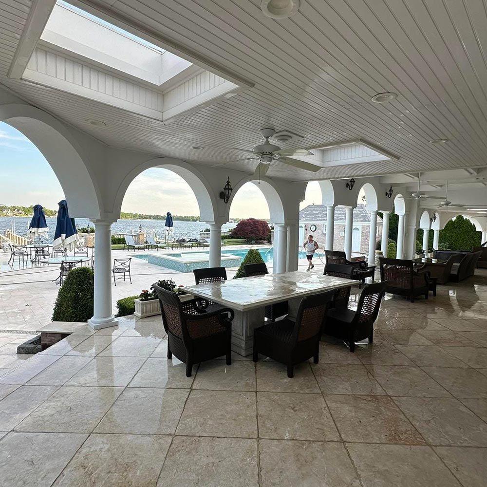 A large room with a table and chairs and a pool in the background