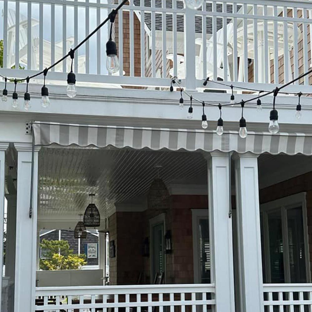 A porch with a striped awning and string lights