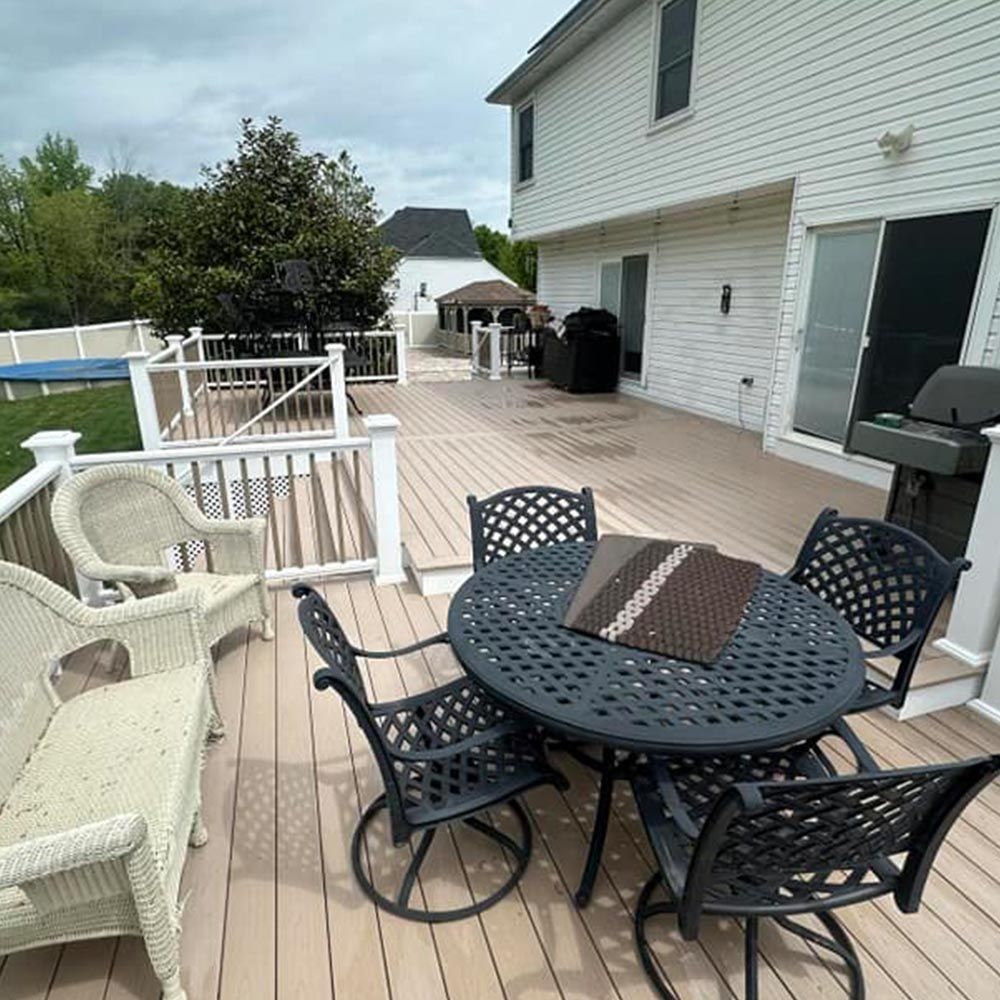 There is a table and chairs on the deck of a house.