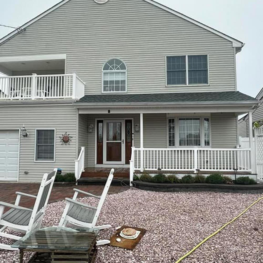 A large house with a porch and rocking chairs in front of it.