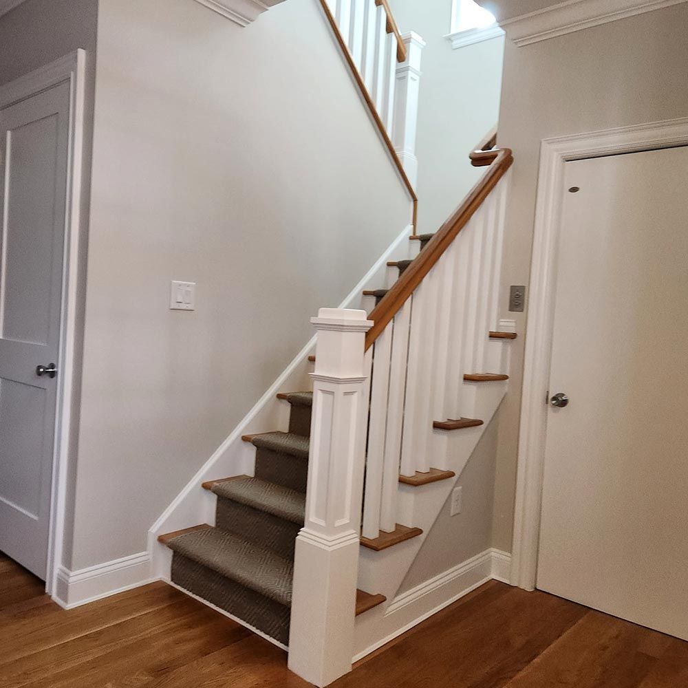 A staircase with a wooden railing and carpeted steps