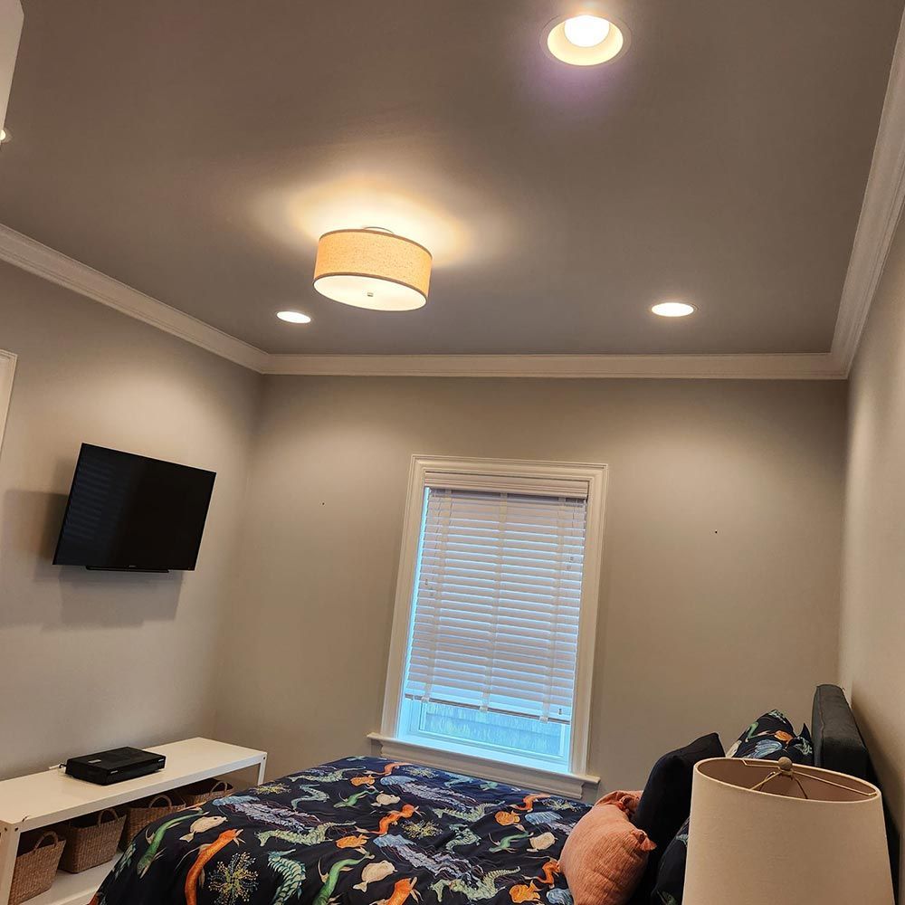 A bedroom with a bed , television , lamp and window.