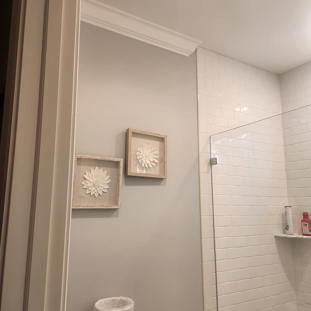 A bathroom with a walk in shower and two paintings on the wall.