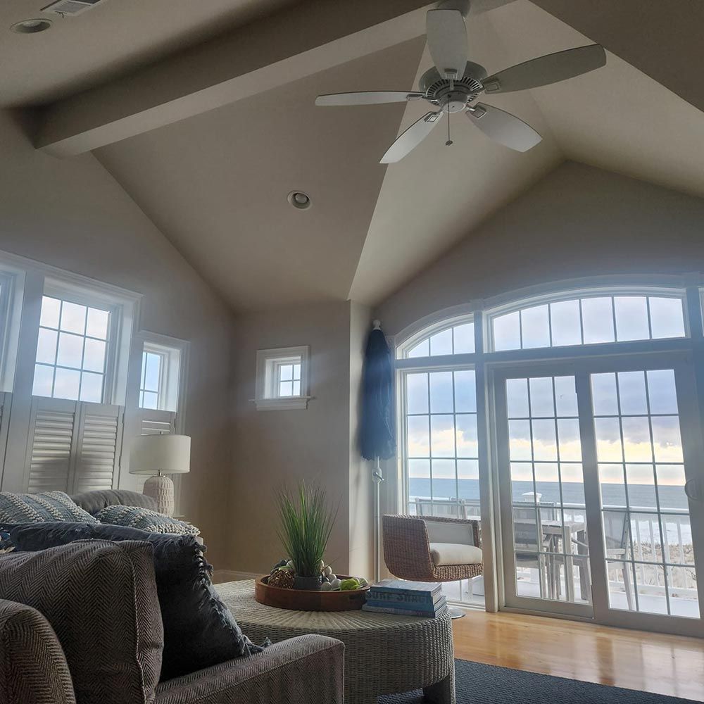 A living room with a lot of windows and a ceiling fan