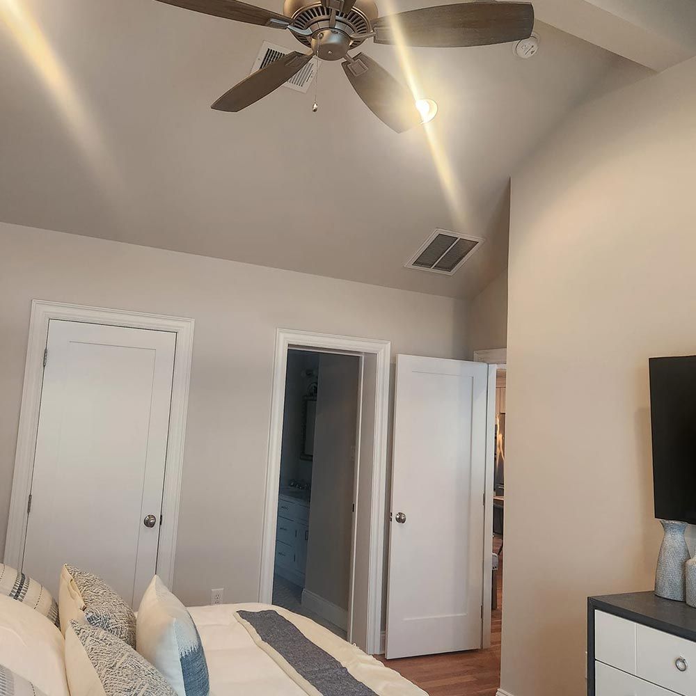 A bedroom with a ceiling fan and a bed.