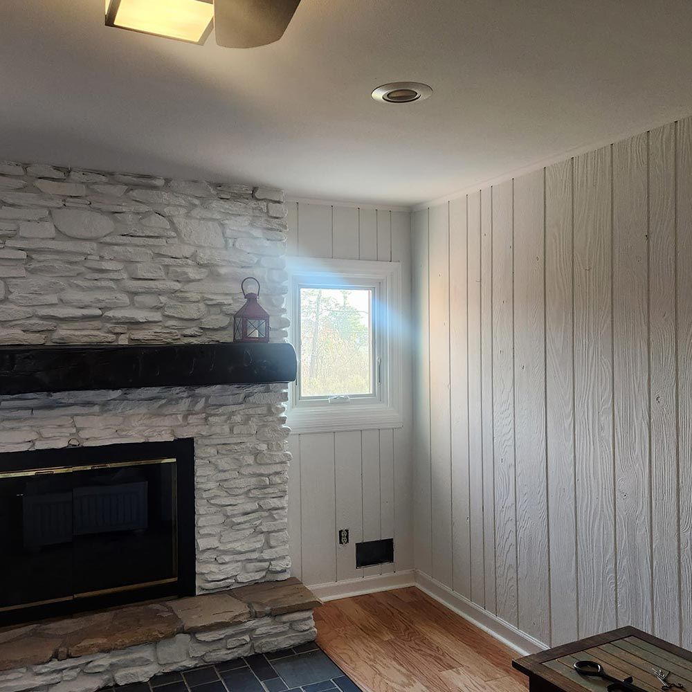 A living room with a stone fireplace and a window.