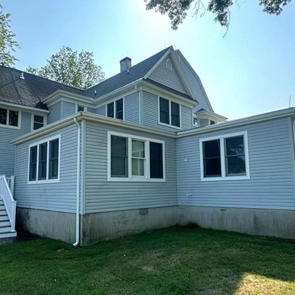 A large house with a lot of windows is sitting on top of a lush green field.