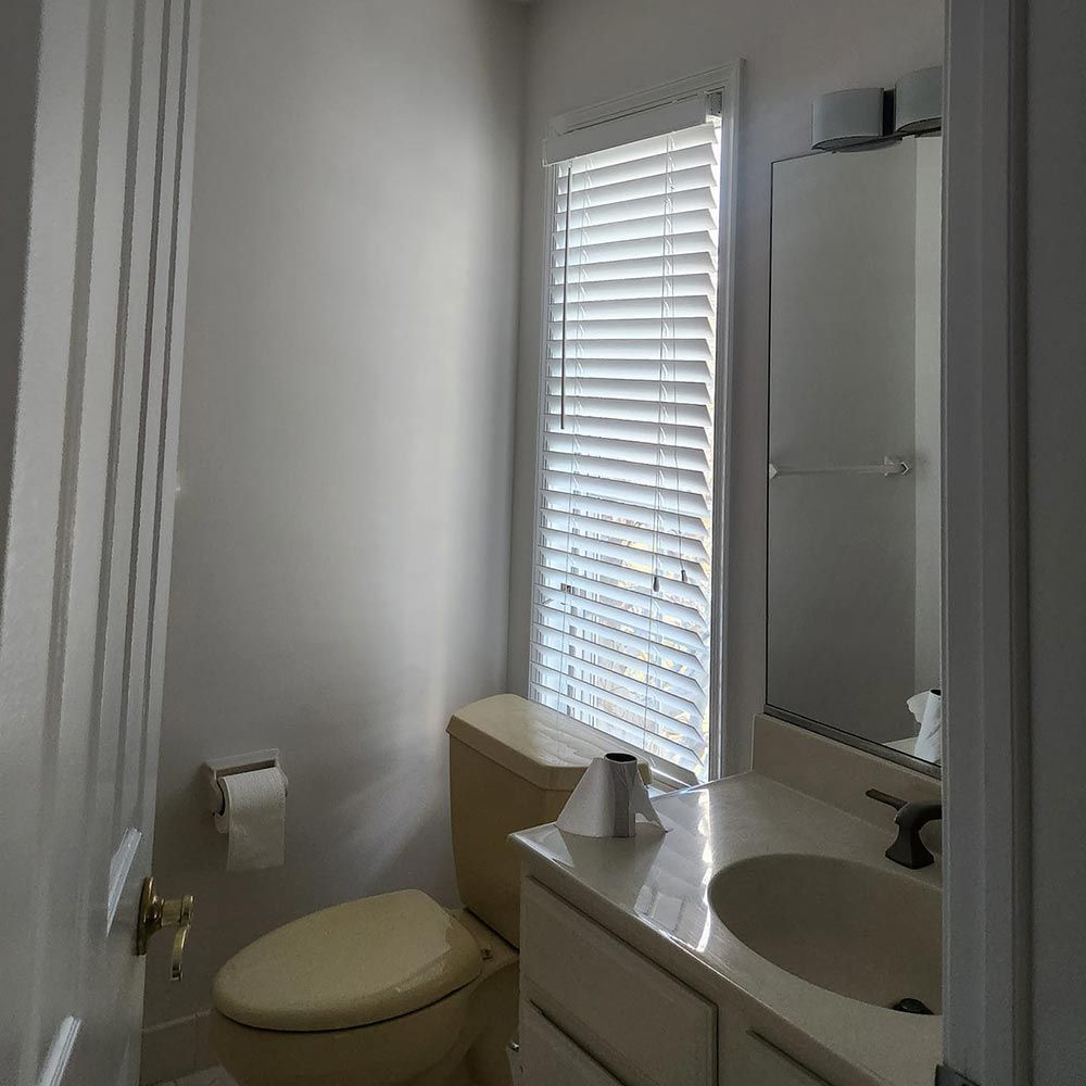 A bathroom with a toilet a sink and a window