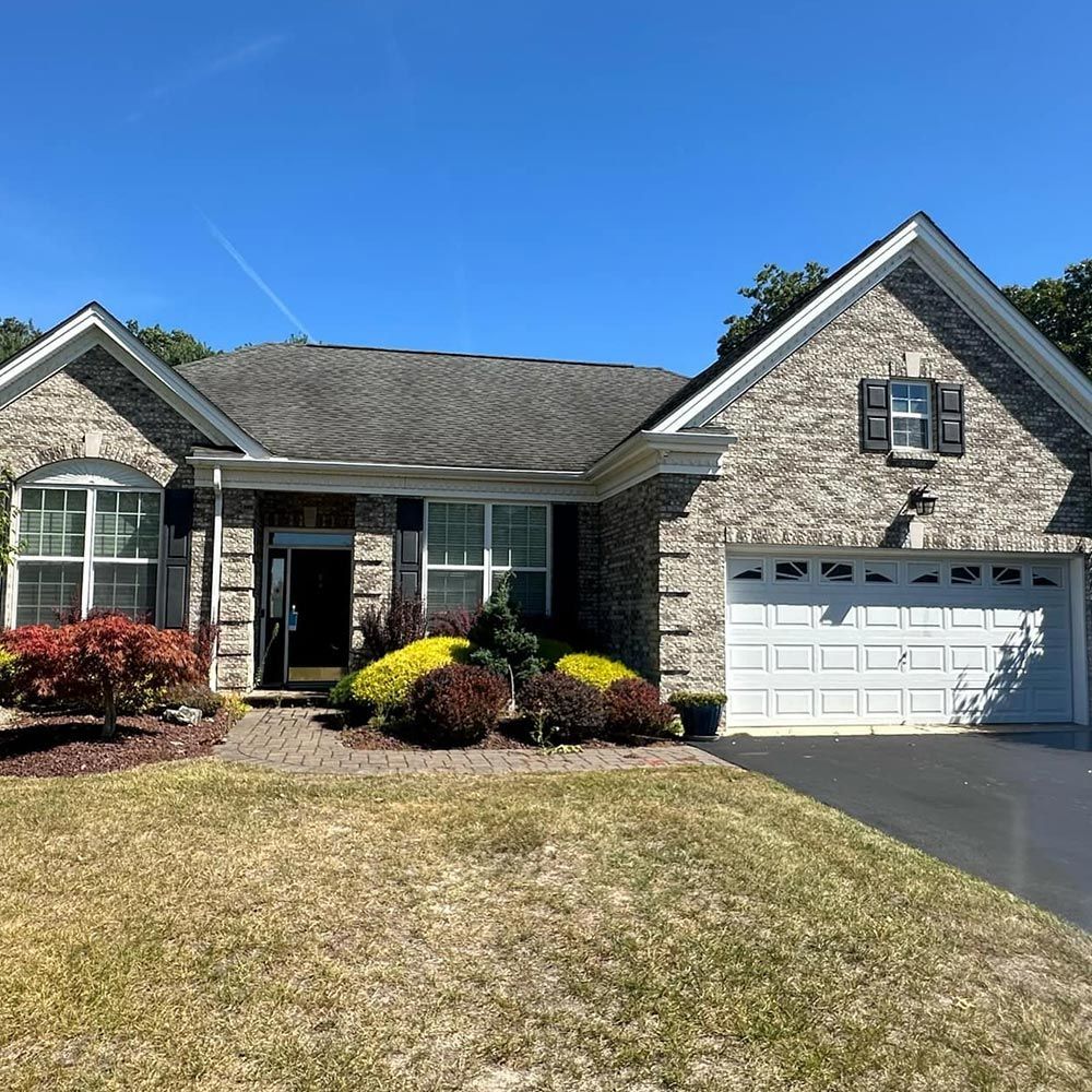 A brick house with a white garage door and a blue sky in the background.