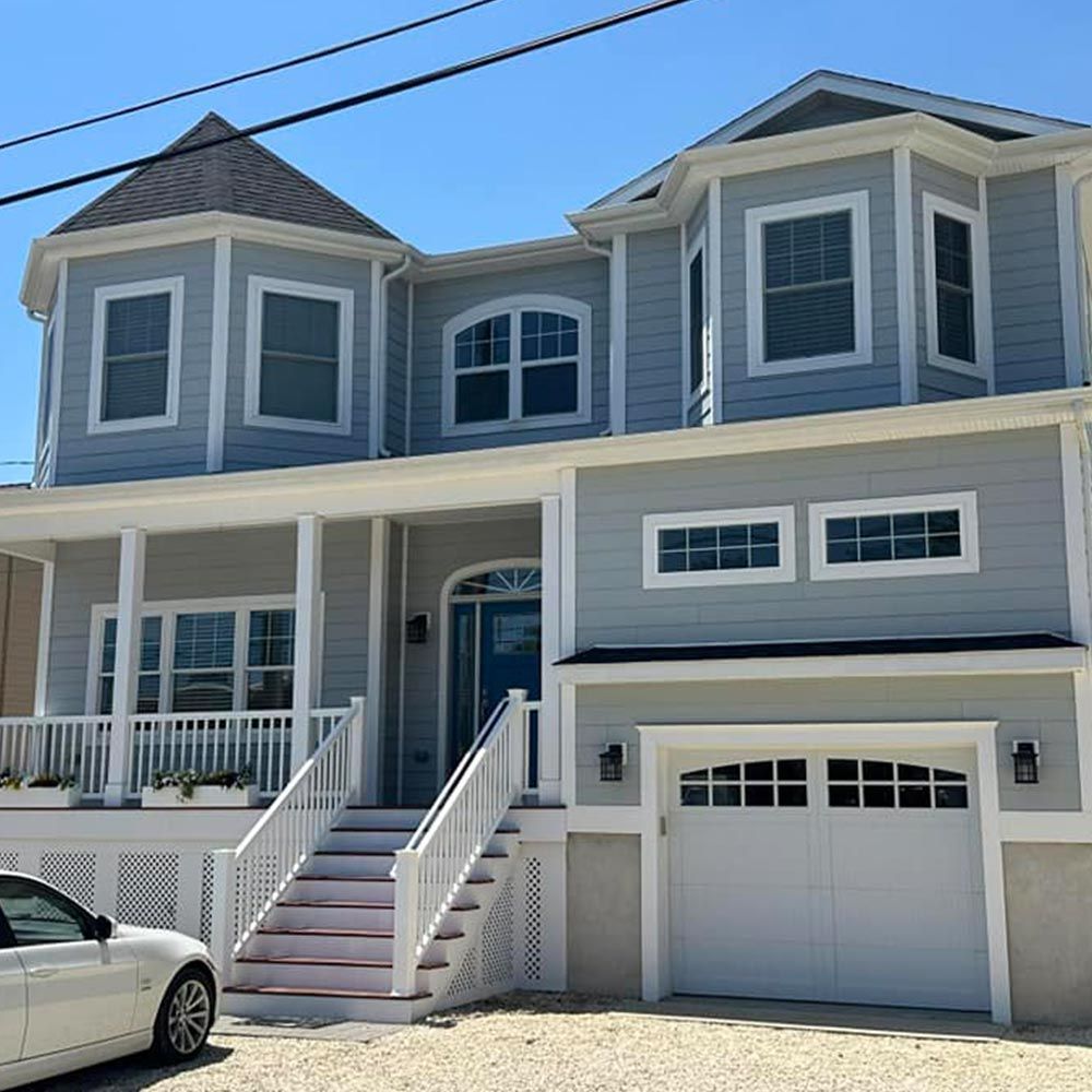 A white car is parked in front of a large house