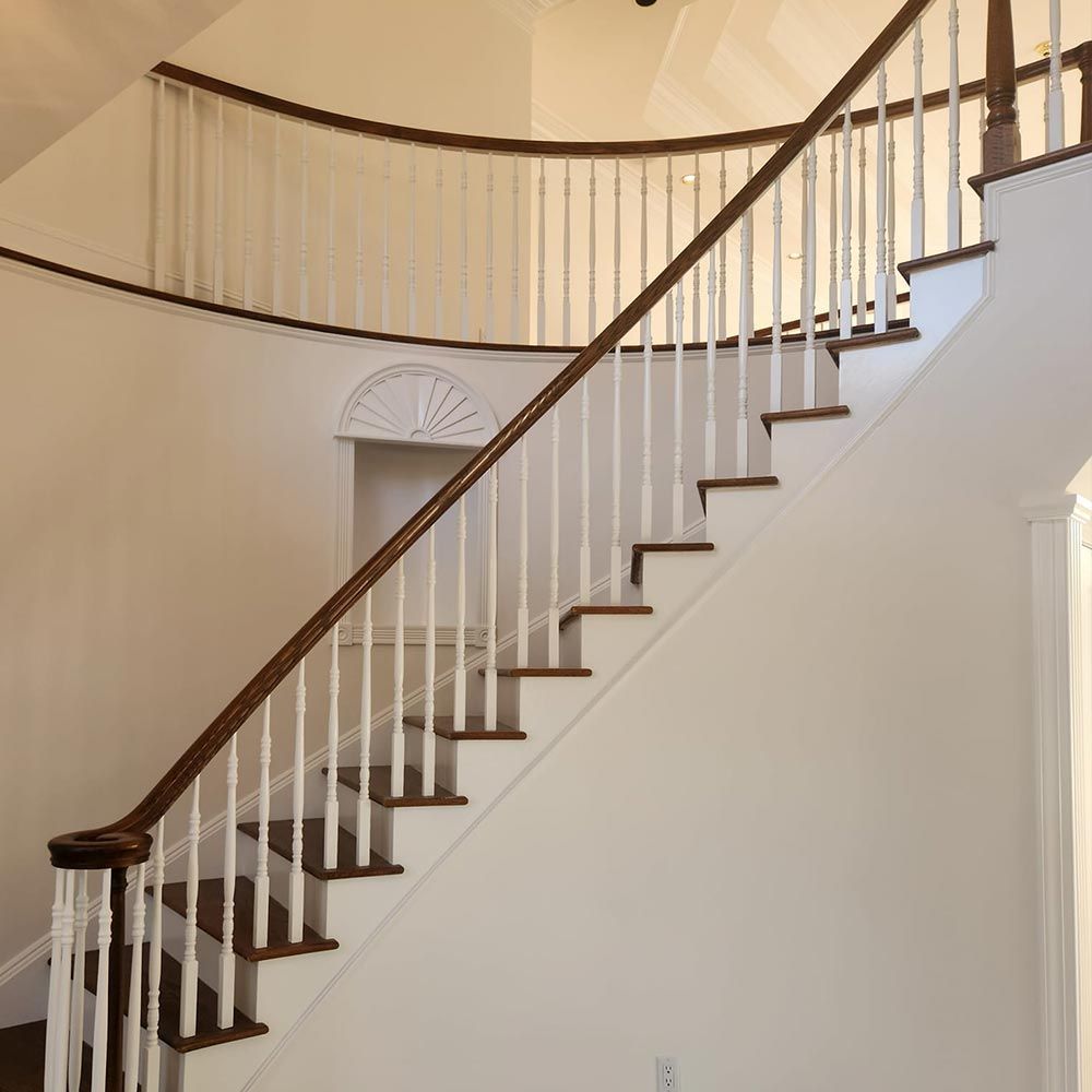 A curved staircase with white railings and wooden steps