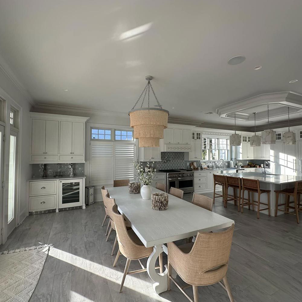 A kitchen with a long white table and chairs