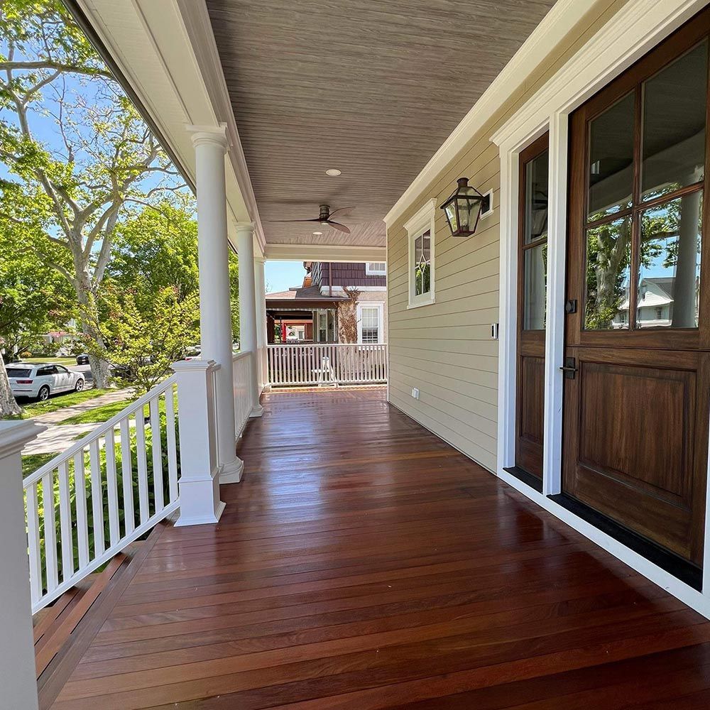 A porch with a wooden floor and a white railing