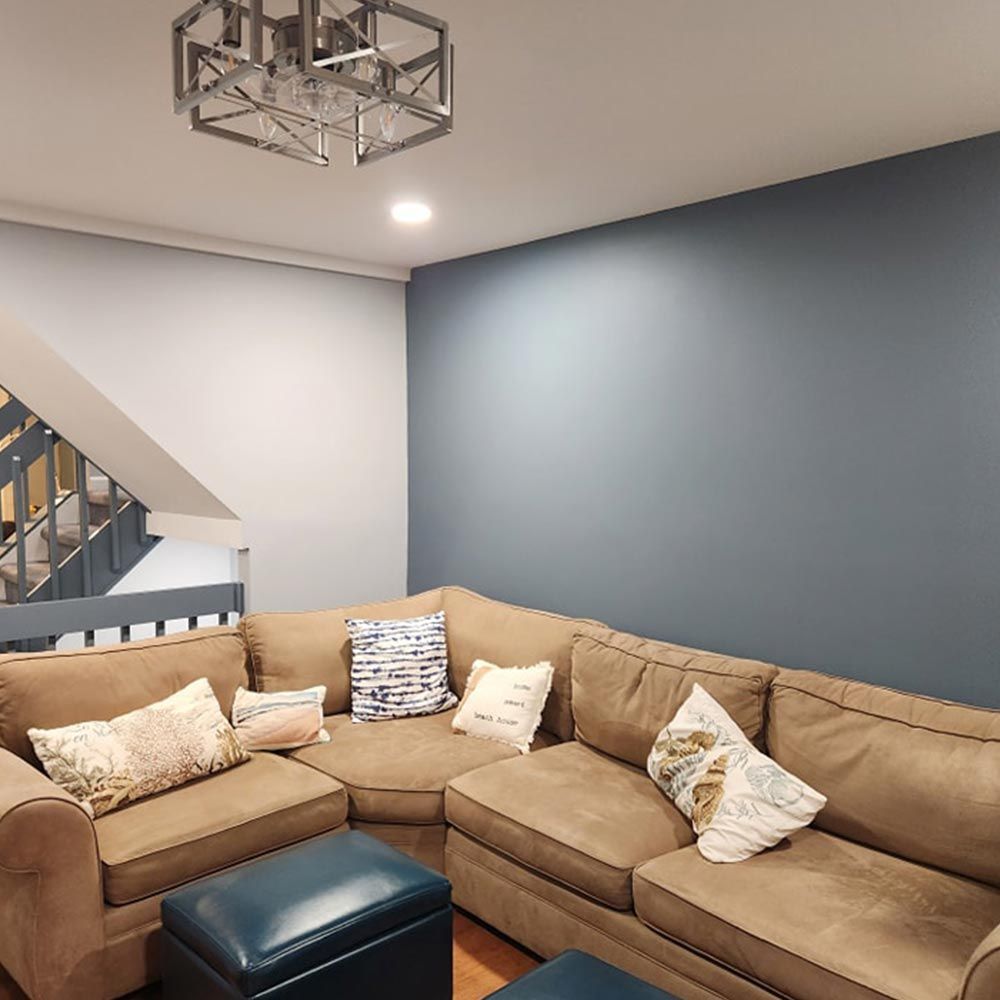 A living room with a sectional couch and stairs