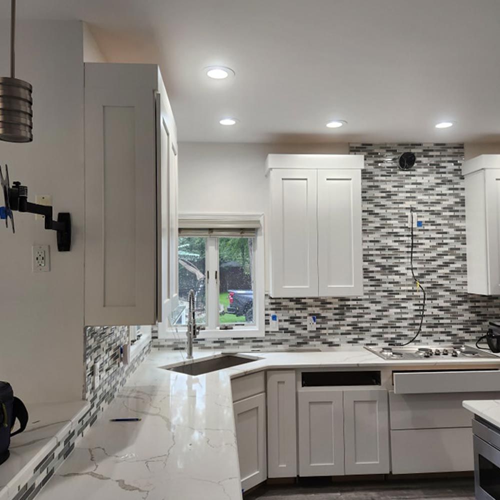 A kitchen with white cabinets and a marble counter top