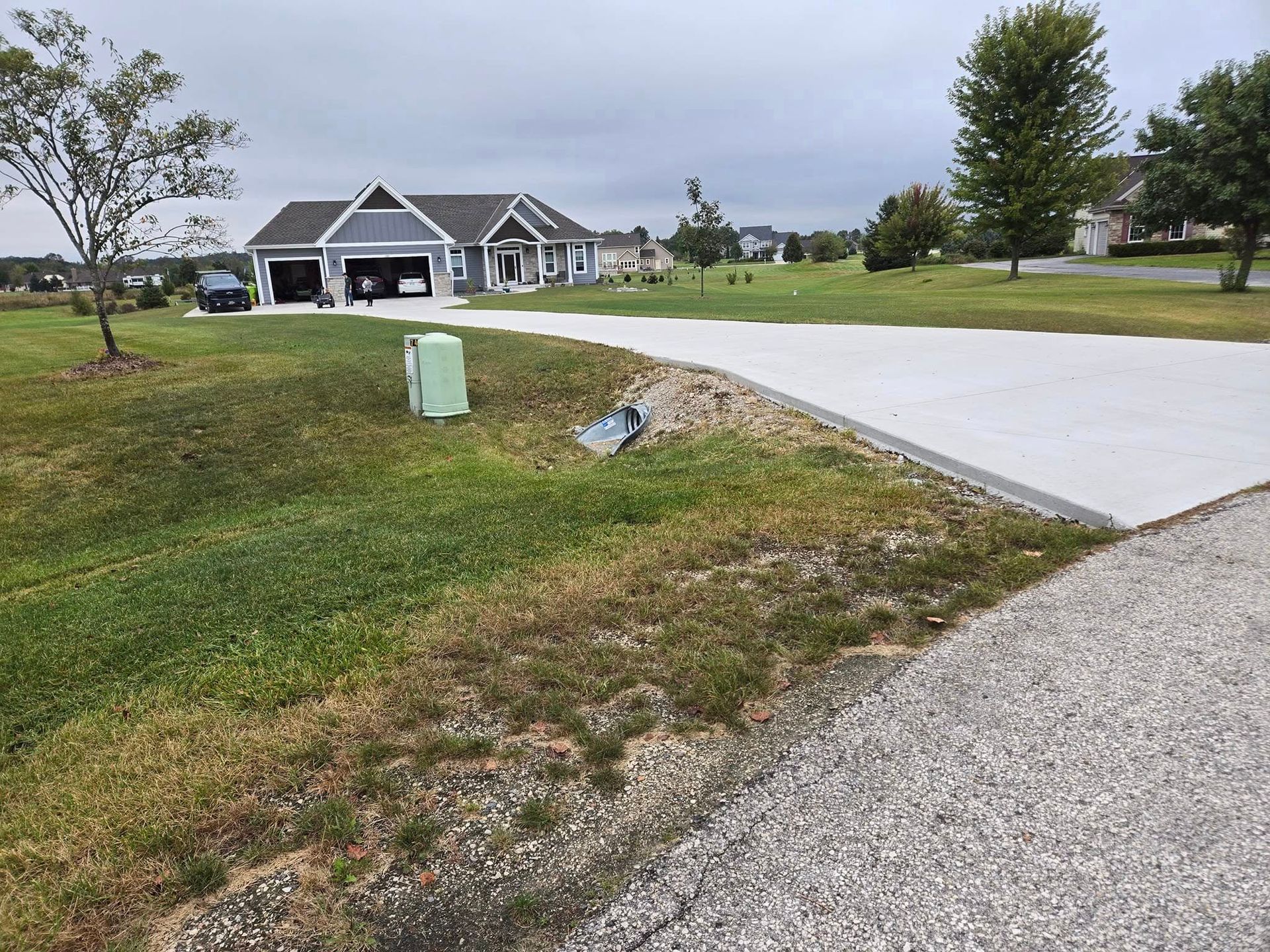 A concrete driveway leading to a house in a residential area.