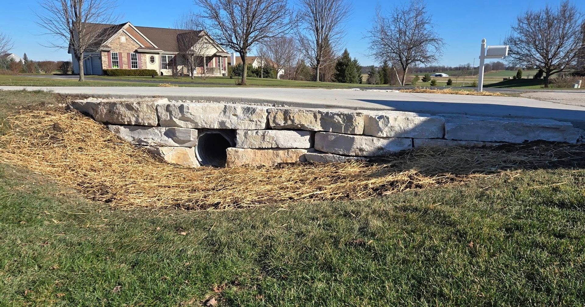 A large house is behind a stone wall next to a road.