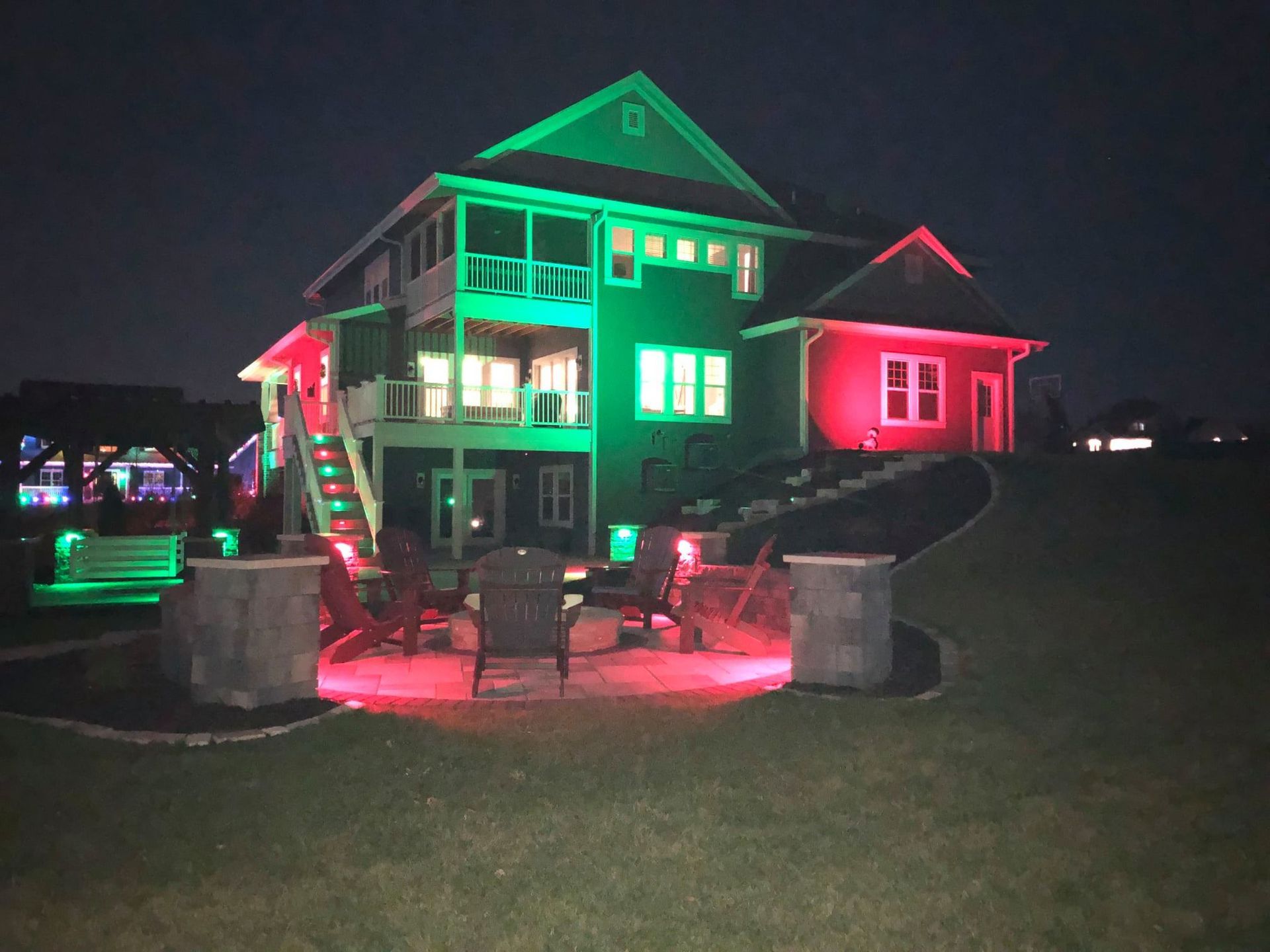 A large house is lit up with green and red lights at night.