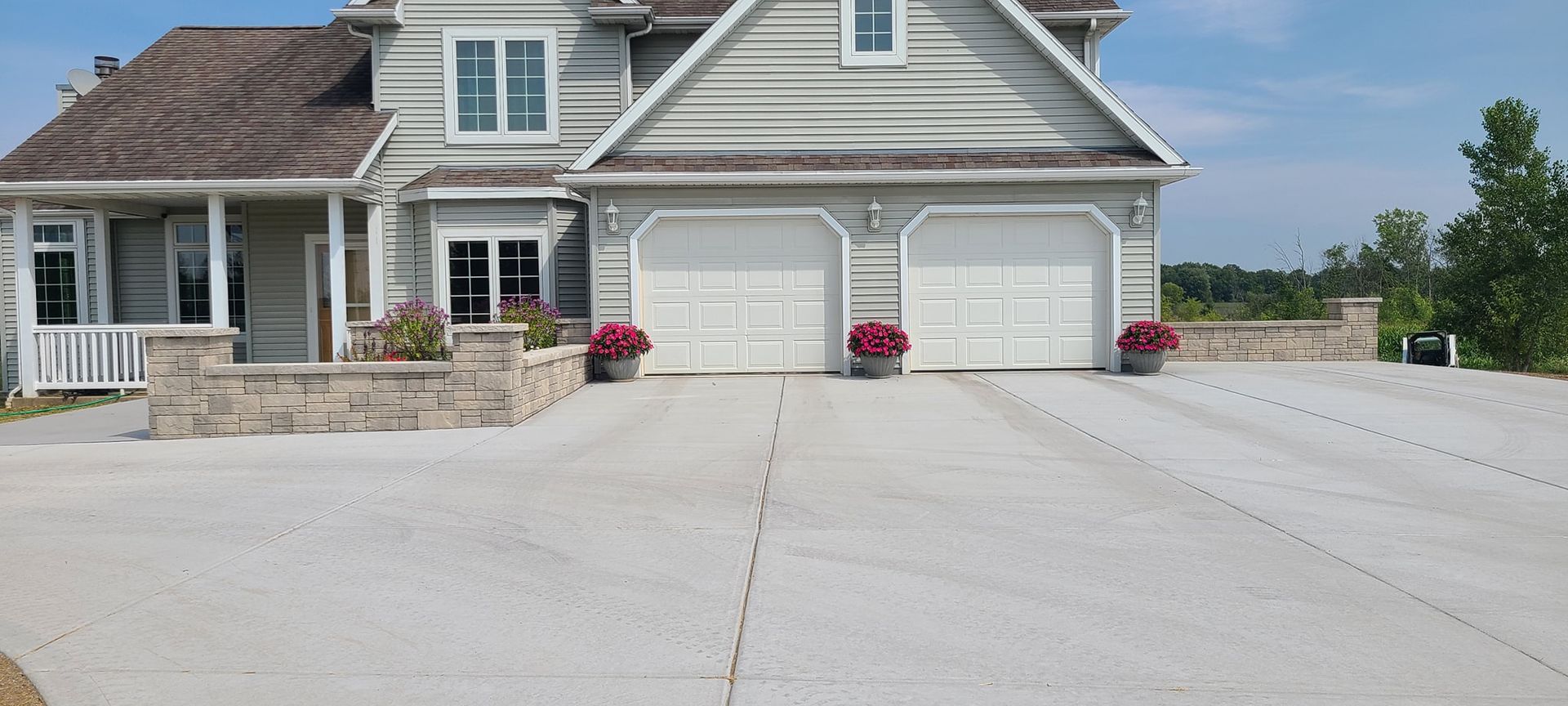 A large white house with a concrete driveway in front of it.