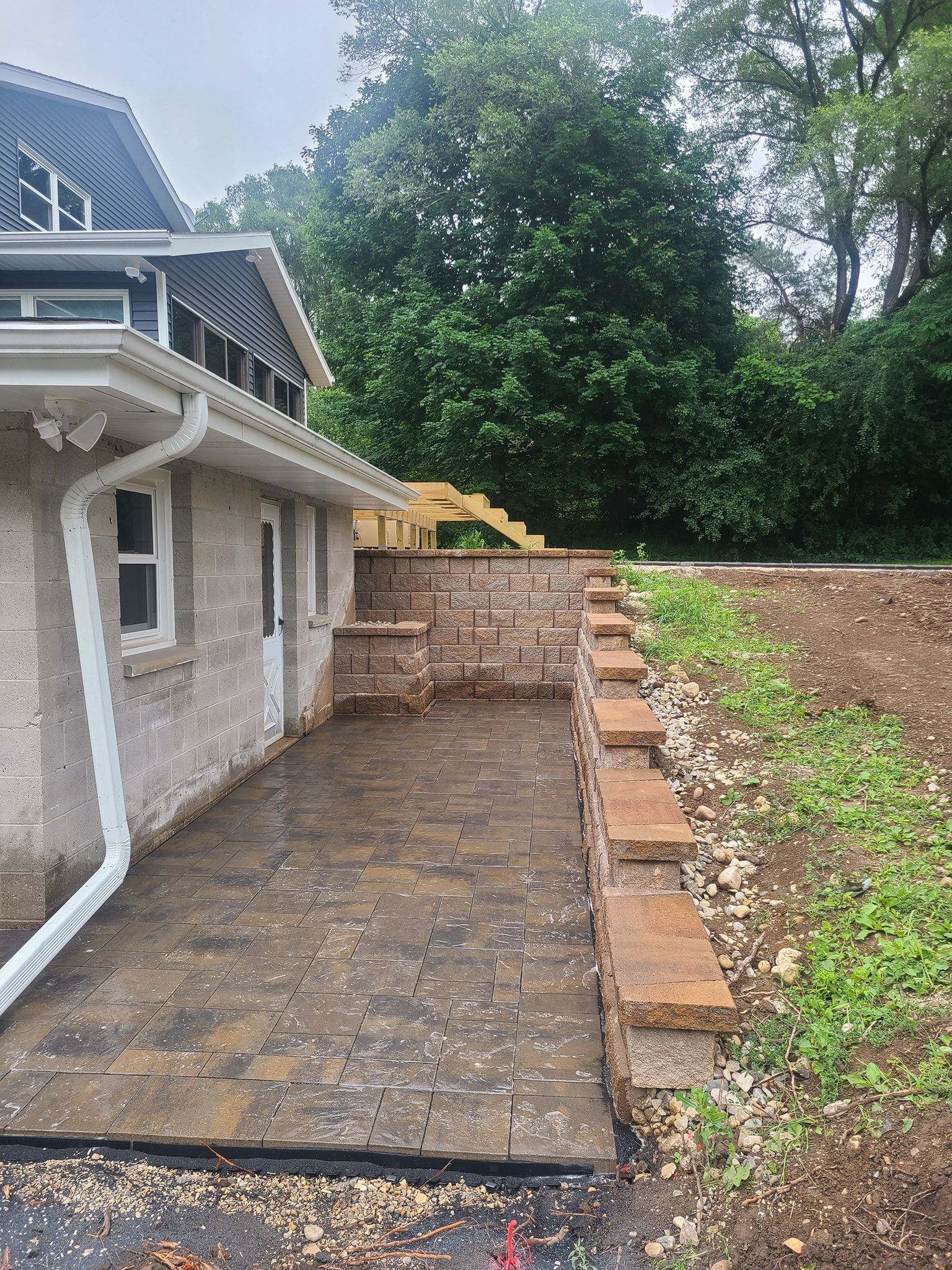 A house with a patio and a stone wall in front of it.