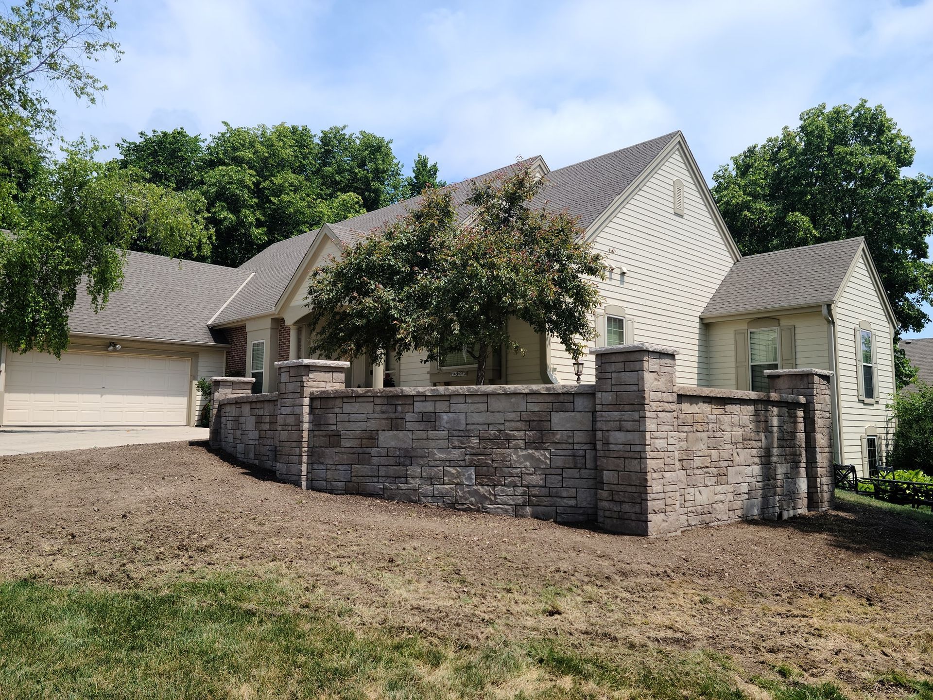 A large house with a stone wall in front of it