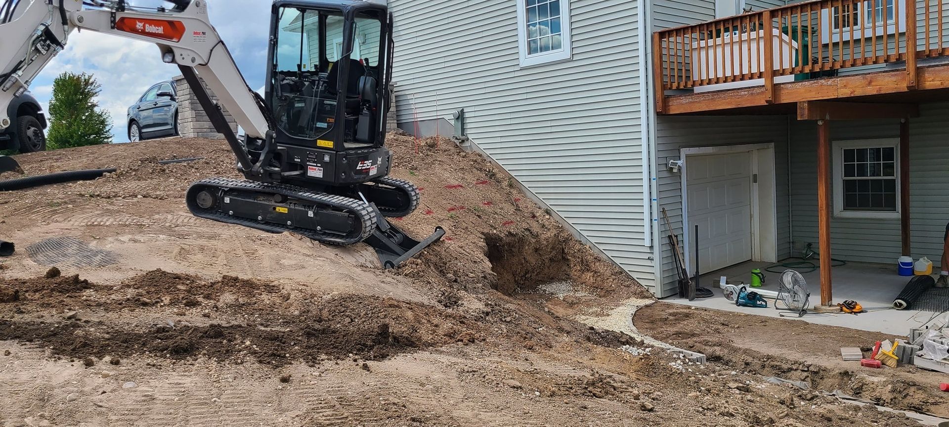 A bulldozer is digging a hole in the dirt in front of a house.